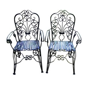 May include: Two black wrought iron chairs with ornate scrollwork and slatted seats. The chairs have a vintage style and are perfect for outdoor dining or lounging.