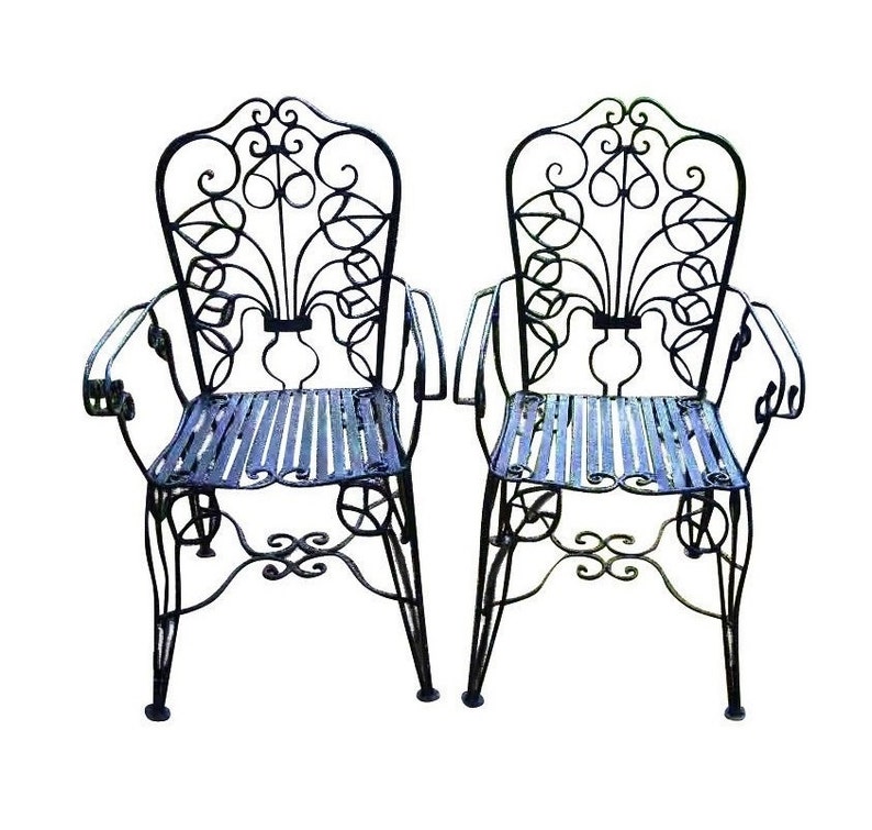 May include: Two black wrought iron chairs with ornate scrollwork and slatted seats. The chairs have a vintage style and are perfect for outdoor dining or lounging.