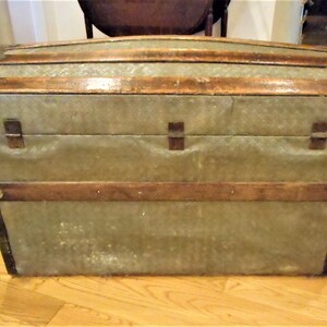 May include: A vintage green canvas and wood travel trunk with brass hardware and a wood frame.