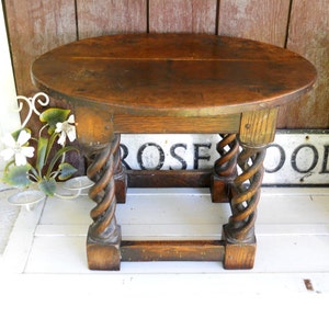 May include: A dark brown wooden table with a round top and twisted legs. The table is made of solid wood and has a rustic finish.