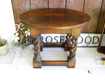 May include: A dark brown wooden table with a round top and twisted legs. The table is made of solid wood and has a rustic finish.
