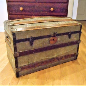 May include: A vintage wooden and metal trunk with a green painted exterior and brass hardware. The trunk has a hinged lid and a lock with a keyhole.