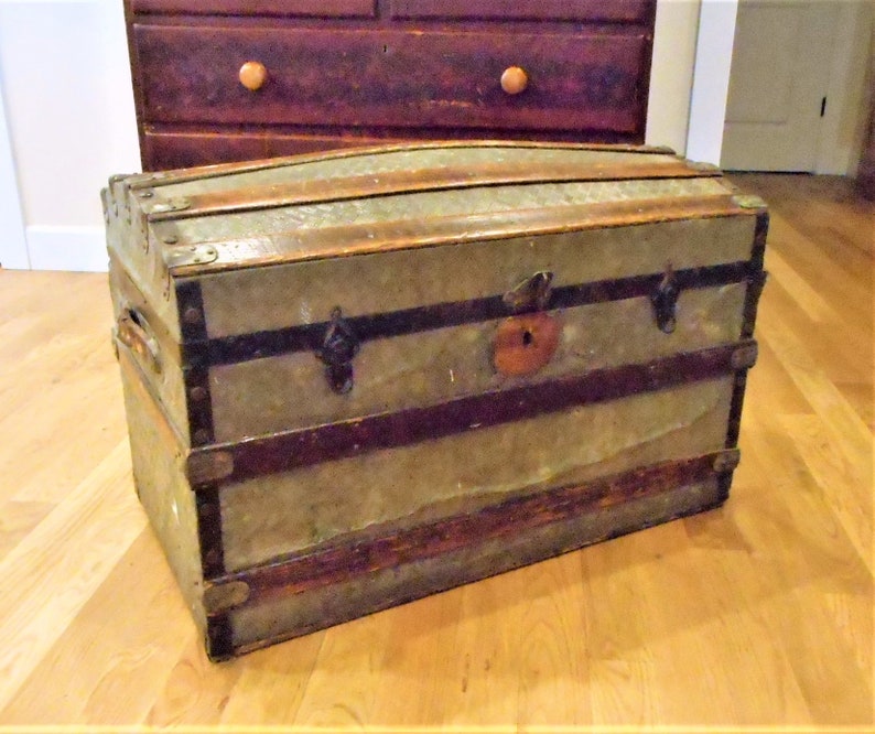 May include: A vintage wooden and metal trunk with a green painted exterior and brass hardware. The trunk has a hinged lid and a lock with a keyhole.