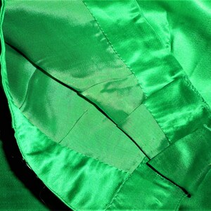 K&ouml;nnte beinhalten: Nahaufnahme des Innenfutters eines Kleidungsst&uuml;cks aus gr&uuml;nem Satin. Der Stoff ist &uuml;ber sich selbst gelegt und zeigt die N&auml;hte und die glatte Textur des Satins.