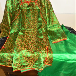 K&ouml;nnte beinhalten: Ein gr&uuml;nes Seidenkleid im chinesischen Stil mit roten und goldenen Blumenstickereien und einem passenden gr&uuml;nen Seidenrock.