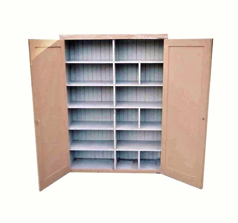May include: A vintage wooden cabinet with two doors and multiple shelves. The cabinet is painted a light beige color and has a white interior.