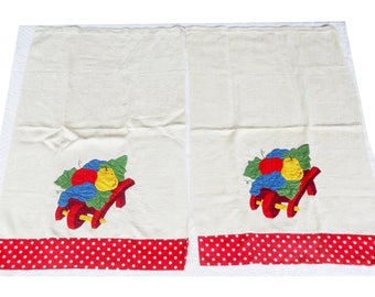 May include: Two white tea towels with red polka dot borders. Each towel features an embroidered design of a red wagon filled with fruit, including a red apple, yellow pear, and blue grapes.