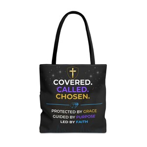 Può includere: Una borsa tote nera con due manici neri caratterizzata da un'icona a croce dorata e dal testo COVERED. CALLED. CHOSEN. seguito da un grafico a diamante e dal testo PROTECTED BY GRACE, GUIDED BY PURPOSE, LED BY FAITH in lettere bianche, viola e dorate.