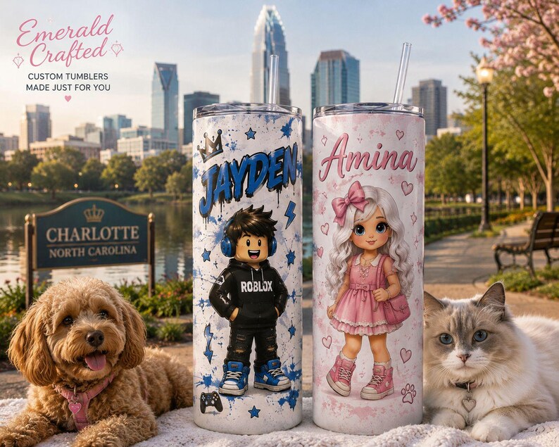 May include: Two cylindrical tumblers with clear straws. The left tumbler features a blue graffiti-style name JAYDEN, a cartoon character in a black Roblox hoodie, and blue stars. The right tumbler features the name Amina, a cartoon girl in a pink dress, and hearts.
