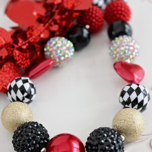 May include: A red, black, gold, and white chunky bead necklace with a checkerboard pattern, rhinestones, and a large red bead.