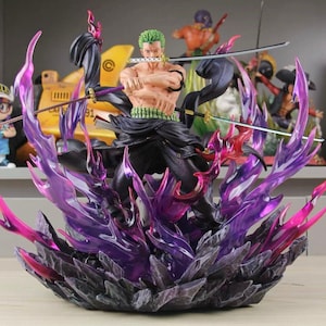 Puede incluir: Una figura de anime de Roronoa Zoro con pelo verde, sin camisa, con pantalones oscuros y una faja verde. El personaje sostiene tres espadas, una en la boca y dos en las manos, rodeado de efectos de llamas púrpuras translúcidas sobre una base oscura.