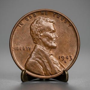 Può includere: Una moneta da un centesimo degli Stati Uniti color rame che presenta il profilo di Abraham Lincoln rivolto verso destra. Il testo IN GOD WE TRUST è arcuato in alto, LIBERTY è a sinistra e l'anno 1943 con il segno di zecca S è a destra.