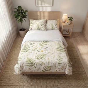 May include: A bed featuring a white duvet cover and two matching pillowcases decorated with a botanical print of green fern leaves and small yellow wildflowers. The bedding set is displayed on a wooden bed frame with a light wood headboard.