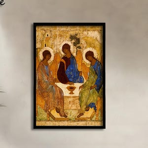 May include: A rectangular wall art print featuring a reproduction of the Holy Trinity icon by Andrei Rublev, enclosed in a thin black frame. The artwork depicts three figures seated around a table with a chalice, rendered in gold, blue, and red tones.