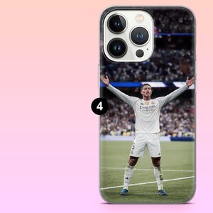 May include: A clear smartphone case featuring a printed image of a soccer player in a white uniform with the number 5 on the shorts, standing on a green field with arms outstretched. The case has a cutout for a triple-lens camera system.
