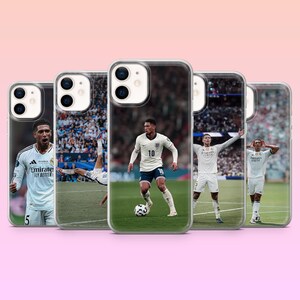 May include: Five clear smartphone cases featuring photographic prints of a soccer player in a white jersey. The images show the athlete in various poses on a green field, including running with a ball, celebrating, and performing a bicycle kick.