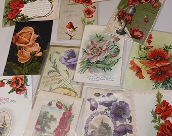 May include: A collection of vintage postcards featuring floral designs. The postcards have various colors, including red, pink, white, and green. Some of the postcards have text, such as "Birthday Greetings" and "Wishing You Many Happy Returns".