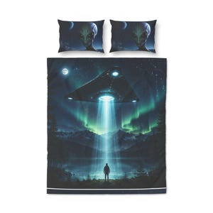 Peut inclure: Ensemble de literie avec une scène d'OVNI. La housse de couette et les deux taies d'oreiller présentent un ciel nocturne avec un extraterrestre, une personne et un faisceau lumineux. Le paysage comprend des montagnes, des arbres et des aurores boréales. Couleurs : bleu, vert et noir.