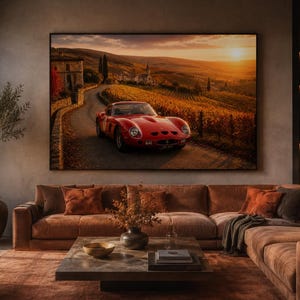 May include: A large rectangular wall art print featuring a red vintage sports car driving on a winding road through a golden vineyard at sunset. The scene includes rolling hills, stone buildings, and warm light, framed in a thin black border.