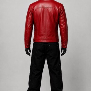 May include: A vibrant red leather jacket with a structured collar, long sleeves, and buttoned cuffs, paired with loose-fitting black trousers featuring side pockets and metallic rivets, displayed on a mannequin against a neutral gray background.