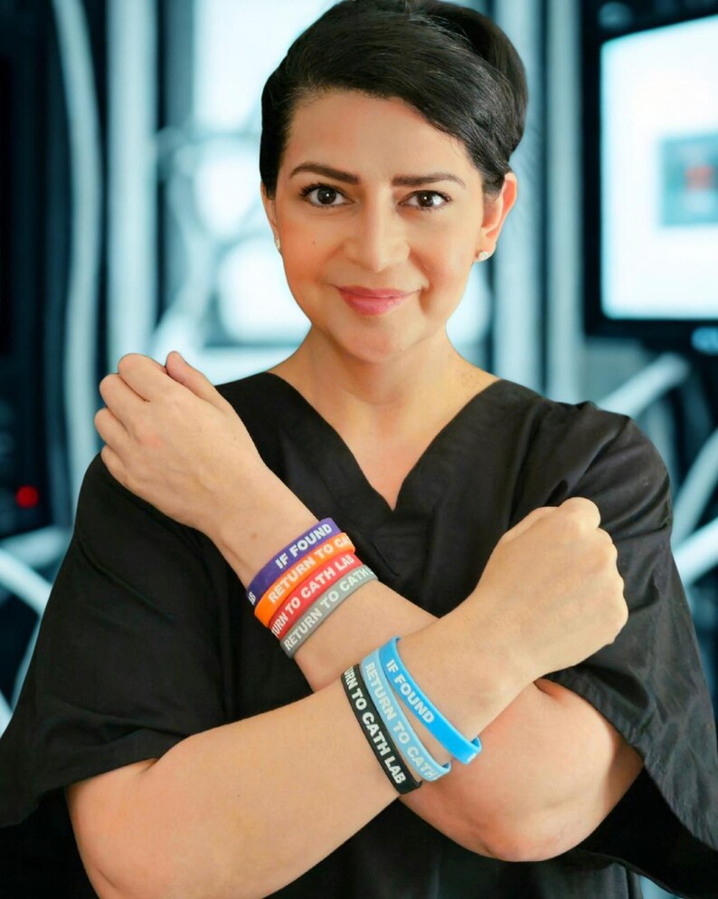 Puede incluir: Un conjunto de pulseras de silicona en colores morado, naranja, gris, azul claro y negro. Cada pulsera presenta el texto impreso en blanco IF FOUND RETURN TO CATH LAB. Las pulseras se llevan en las mu&ntilde;ecas, mostrando el texto claramente.