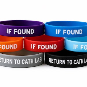 Puede incluir: Una colecci&oacute;n de seis pulseras de silicona en colores morado, azul, naranja, rojo, azul claro, gris y negro. Cada banda presenta texto blanco en relieve. Las bandas superiores dicen IF FOUND, las inferiores dicen RETURN TO CATH LAB.