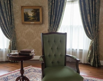 Antique style tufted green accent chair with cane side panels and upholstered armrests