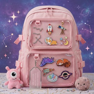 May include: A light pink backpack with two clear front pockets containing various space-themed enamel pins. A rectangular tag reads COSMIC EXPLORER ITA COLLECTOR VOYAGER SER. A pink one-eyed plush toy and a brown moon plush toy sit at the base.