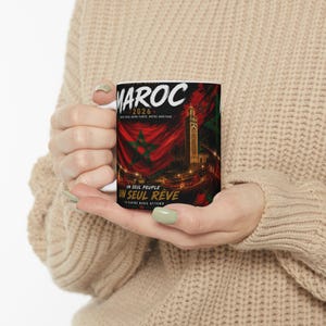 Peut inclure: Un mug en céramique blanc avec le mot "MAROC" en blanc, et "2026" en dessous. Le design comprend un drapeau marocain, un minaret et les phrases "UN SEUL PEUPLE" et "UN SEUL RÊVE".
