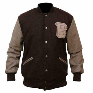 Op de afbeelding: Een donkerbruin varsity jack met lichtbruine mouwen, een opstaande kraag en een sluiting met drukknopen. Het jack heeft twee zijzakken met lichtbruine biezen en een grote, lichtbruine letter B als applicatie op de linkerborst.