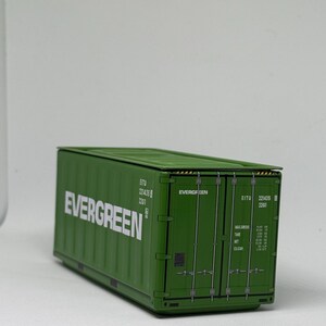 May include: A green rectangular shipping container model featuring the white text EVERGREEN on the side. The container has vertical corrugated panels, double doors with locking bars, and technical identification markings including EITU 221435 22G1.