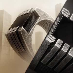 May include: A silver-toned ring with a distressed, brushed metal finish featuring a prominent rectangular black inlay. The band displays a series of parallel vertical grooves and a textured, cross-hatched pattern along the sides and inner surface.