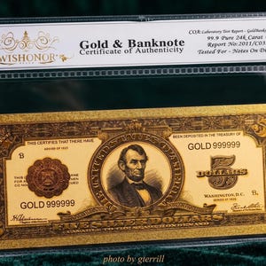 May include: A gold-colored replica five-dollar banknote featuring a portrait of Abraham Lincoln, enclosed in a clear protective sleeve with a certificate of authenticity header labeled WISHONOR Gold & Banknote, 99.9 Pure 24k Carat Gold.