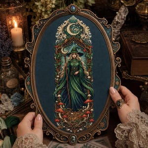 May include: An oval-framed cross-stitch embroidery featuring a central figure in a long green gown and pointed hat, holding a staff with a crescent moon. The design includes forest elements, red mushrooms, and a large crescent moon on a dark blue fabric.