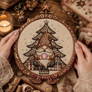 May include: A circular wooden embroidery hoop containing a cross-stitch design of a gnome with a long white beard, wearing a brown hat shaped like a Christmas tree decorated with stars and a crescent moon, holding a pink orb, surrounded by gifts.