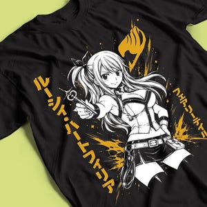 Puede incluir: Una camiseta negra con una ilustración gráfica en blanco de un personaje de anime de pelo largo sosteniendo una llave. El diseño incluye salpicaduras de pintura amarilla, el emblema del gremio Fairy Tail y caracteres japoneses verticales.