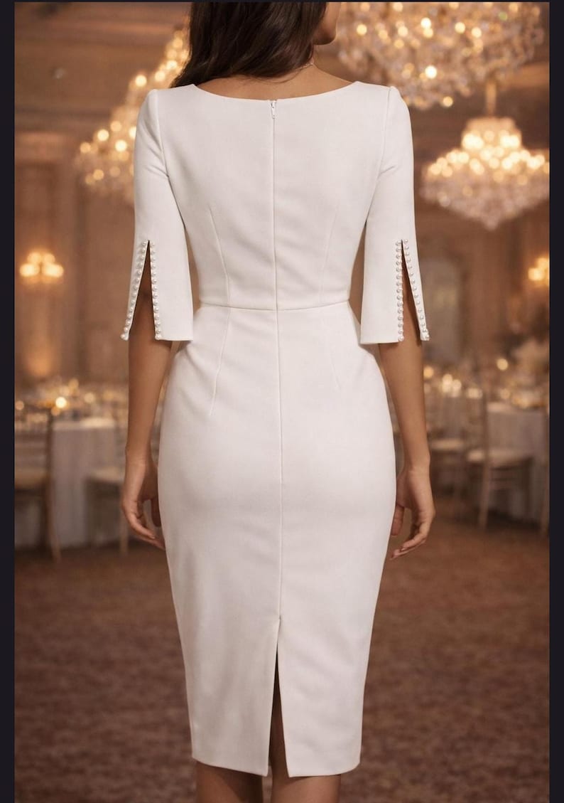 May include: A white knee-length sheath dress featuring a boat neckline, elbow-length sleeves with vertical side slits, and a row of small white buttons lining each sleeve opening. The dress has a fitted silhouette with a center back zipper closure.