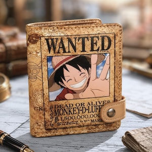 Könnte beinhalten: Ein beigefarbenes Klappportemonnaie mit einem One Piece Monkey D. Luffy Wanted-Poster-Motiv. Das Design enthält den Text WANTED, DEAD OR ALIVE, MONKEY D. LUFFY und 1.500.000.000. Ein kleiner beiger Riemen mit einem Metalldruckknopf verschließt das Portemonnaie.