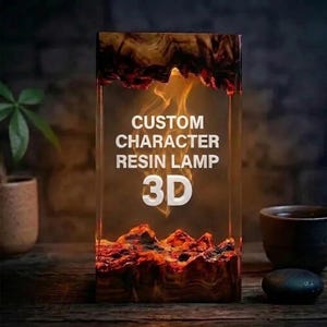 Può includere: Una lampada rettangolare in resina con base e parte superiore in legno scuro e un interno color ambra brillante. Il testo CUSTOM CHARACTER RESIN LAMP 3D è stampato in bianco sulla superficie frontale, illuminato da una fonte di luce interna.