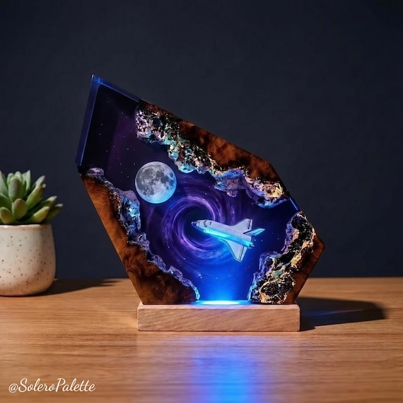 A handcrafted resin lamp trapping a Space Shuttle mid-launch inside a glowing purple black hole — genuinely jaw-dropping galaxy diorama you can't buy at Target.