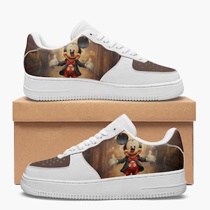 May include: A pair of white low-top sneakers featuring a brown toe box with perforated details and a side panel graphic of a cartoon mouse wearing a black tuxedo, red bowtie, and red shorts, standing in a dimly lit, warm-toned indoor setting.
