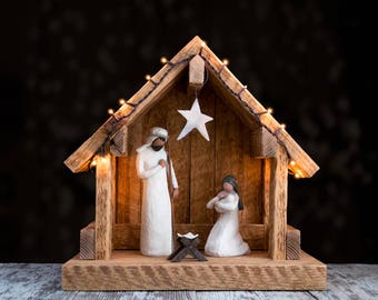 May include: A wooden nativity scene with a star on top and figurines of Mary, Joseph, and baby Jesus inside. The scene is lit with string lights.