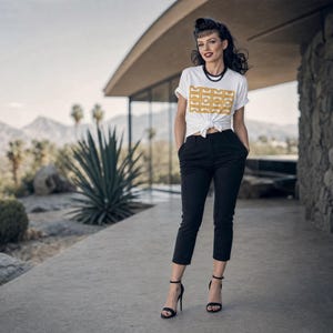Könnte beinhalten: Ein weißes kurzärmeliges T-Shirt mit einem goldenen geometrischen Muster auf der Brust, das an der Taille geknotet ist, kombiniert mit einer schwarzen verkürzten Hose und schwarzen High-Heel-Sandalen. Eine schwarze Perlenkette wird um den Hals getragen.