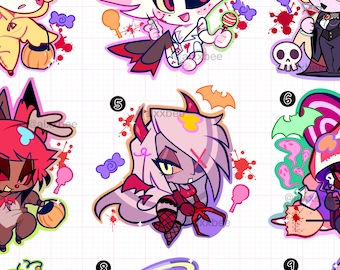 May include: A collection of nine Hazbin Hotel Halloween keychains featuring cartoon characters in costumes, including a duck, nurse, vampire, deer, devil, witch, television head, angel, and mummy, with candy and bat accents.