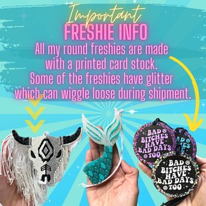 May include: Three hanging ornaments: a white and black bull skull with white fringe, a glittery teal and silver mermaid tail, and round black discs with pink or white glitter edges featuring the text "BAD BITCHES HAVE BAD DAYS TOO".
