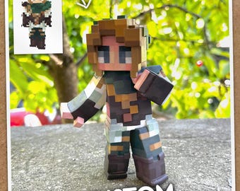 Könnte beinhalten: Eine pixelige Figur eines Charakters mit braunen Haaren, einem grünen Schal und einem braunen und beigefarbenen Outfit. Die Figur steht auf einer Betonoberfläche. Das Wort "CUSTOM" ist in weißer Schrift am unteren Bildrand geschrieben.