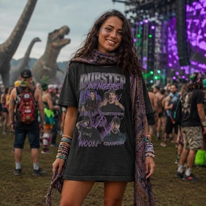 May include: A black short-sleeve t-shirt featuring the text Dubstep Avengers and graphic portraits of four artists labelled Level Up, Subtronics, Wooli, and Crankdat. The shirt is paired with a long, dark patterned scarf, beaded bracelets, and black boots.