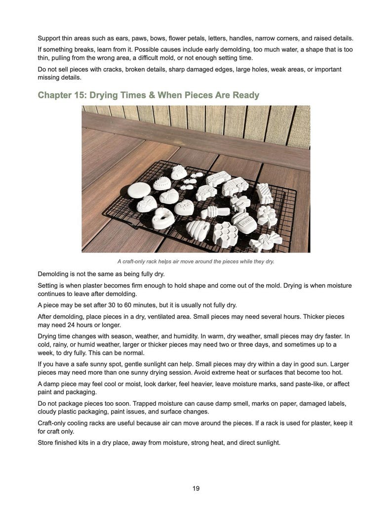 May include: A black wire cooling rack holds numerous small, white, molded plaster shapes in various designs, including hearts, flowers, and geometric patterns, arranged for drying on a wooden surface with instructional text above and below.