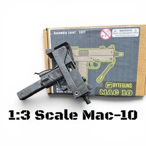 May include: A black 1:3 scale model of a Mac-10 firearm. The model is made of a dark material and is partially assembled. The packaging includes the text "BYTEGUNS MAC 10" and "Assembly Level - EASY".