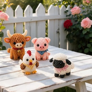 Può includere: Quattro piccole statuette di animali realizzate con minuscole perline: una mucca marrone con un campanellino dorato, un maialino rosa con una bandana a quadri blu, un pollo bianco con una bandana a quadri gialli e una pecora bianca e nera.